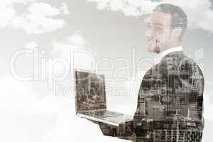 Composite image of businessman looking at camera holding laptop