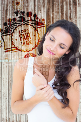 Composite image of pretty brunette eating bar of chocolate