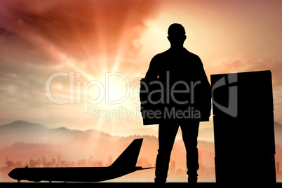 Composite image of confident delivery man holding cardboard box