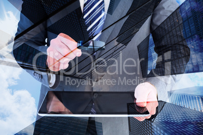 Composite image of businessman looking at tablet with magnifying