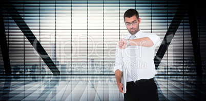 Composite image of serious businessman holding laptop checking t