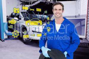 Composite image of confident mechanic holding tire