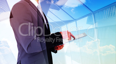 Composite image of businessman using his tablet pc