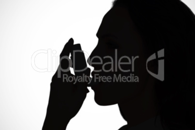 Composite image of asthmatic brunette using her inhaler