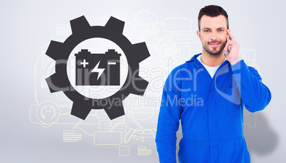 Composite image of smiling male mechanic using his mobile phone