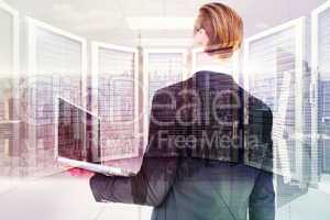 Composite image of businessman looking up holding laptop