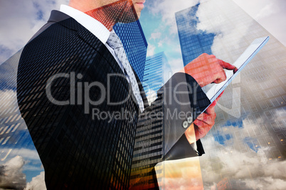 Composite image of businessman using his tablet pc