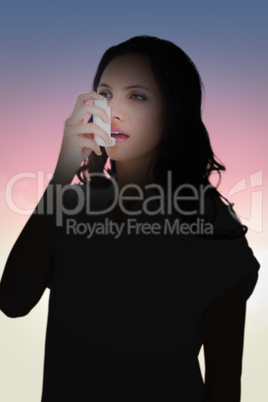 Composite image of asthmatic brunette using her inhaler