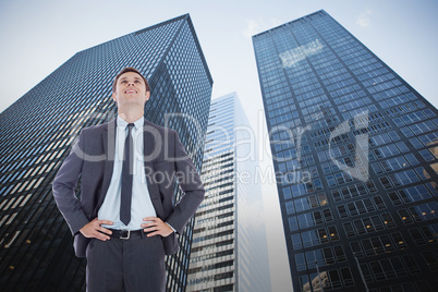 Composite image of smiling businessman with hands on hips