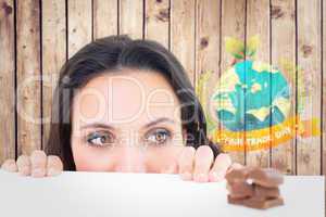 Composite image of pretty brunette peeking at chocolate