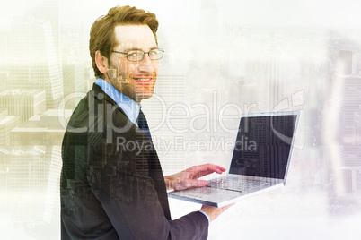 Composite image of smiling businessman using a laptop