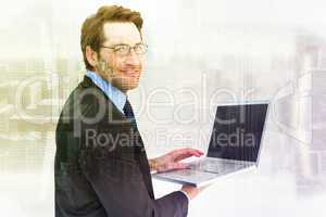 Composite image of smiling businessman using a laptop