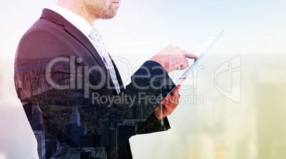 Composite image of businessman using his tablet pc