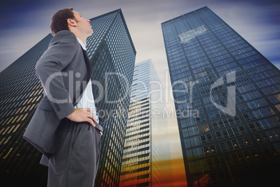 Composite image of stern businessman standing with hands on hips