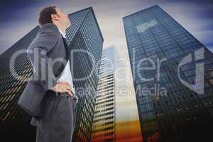 Composite image of stern businessman standing with hands on hips