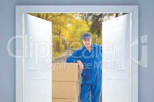 Composite image of happy delivery man leaning on pile of cardboa