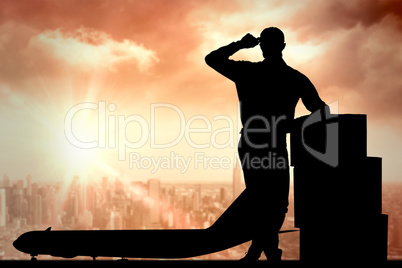 Composite image of happy delivery man leaning on stacked cardboa