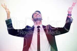 Composite image of businessman cheering with hands raised