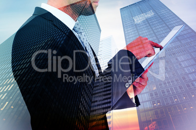 Composite image of businessman using his tablet pc