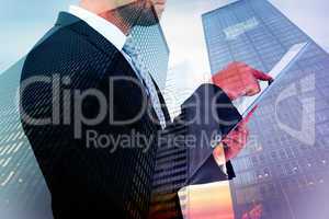 Composite image of businessman using his tablet pc