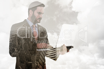 Composite image of focused businessman using his laptop