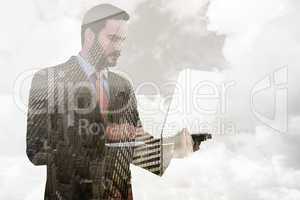 Composite image of focused businessman using his laptop