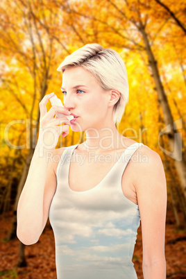 Composite image of blonde woman taking her inhaler