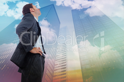 Composite image of stern businessman standing with hands on hips