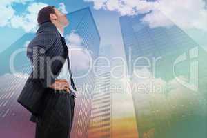 Composite image of stern businessman standing with hands on hips