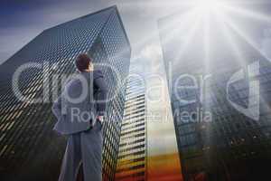 Composite image of businessman standing with hands on hips