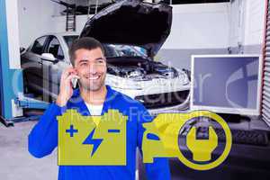 Composite image of smiling male mechanic using mobile phone