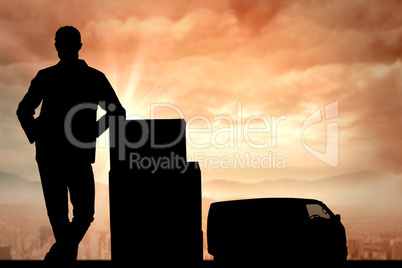 Composite image of smiling delivery man standing by stack of box