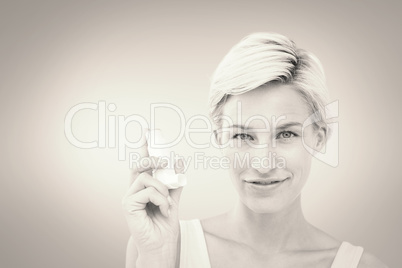 Composite image of pretty woman holding inhaler smiling at camer