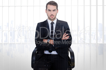 Composite image of serious businessman sitting with arms crossed