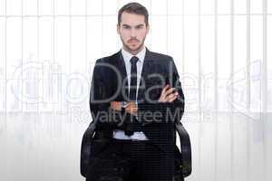 Composite image of serious businessman sitting with arms crossed