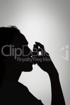 Composite image of asthmatic brunette using her inhaler