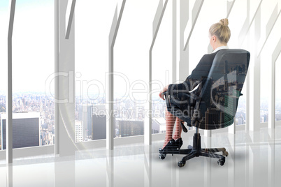 Composite image of businesswoman sitting on swivel chair in blac