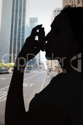 Composite image of asthmatic brunette using her inhaler