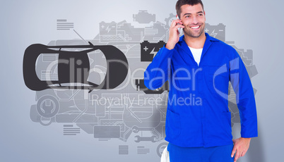 Composite image of smiling male mechanic using mobile phone