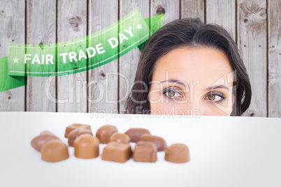 Composite image of pretty brunette peeking at chocolate