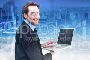 Composite image of smiling businessman using a laptop