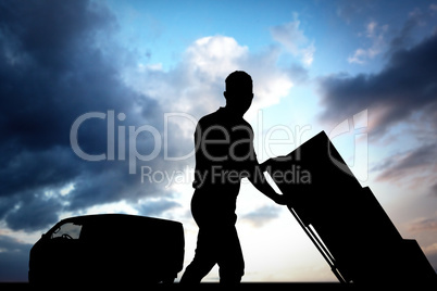 Composite image of delivery man pushing trolley of boxes