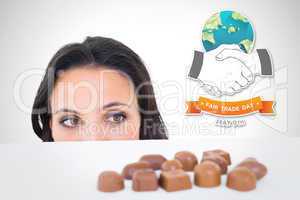 Composite image of pretty brunette peeking at chocolate