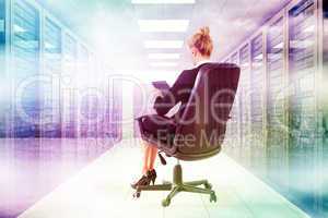 Composite image of businesswoman sitting on swivel chair with ta