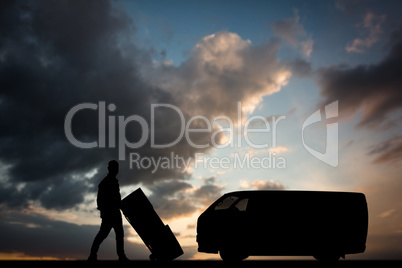 Composite image of happy delivery man pushing trolley of boxes