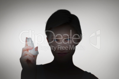 Composite image of pretty woman holding inhaler smiling at camer