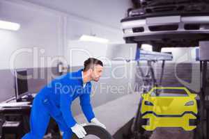 Composite image of mechanic holding tire on white background