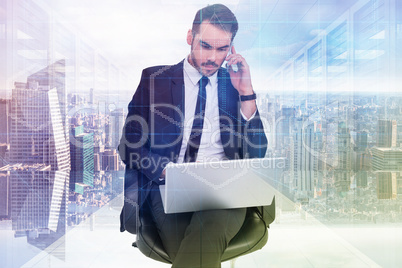 Composite image of businessman using laptop while phoning