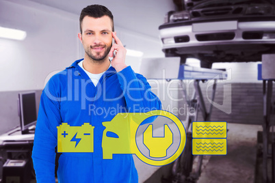 Composite image of smiling male mechanic using his mobile phone