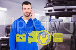 Composite image of smiling male mechanic using his mobile phone